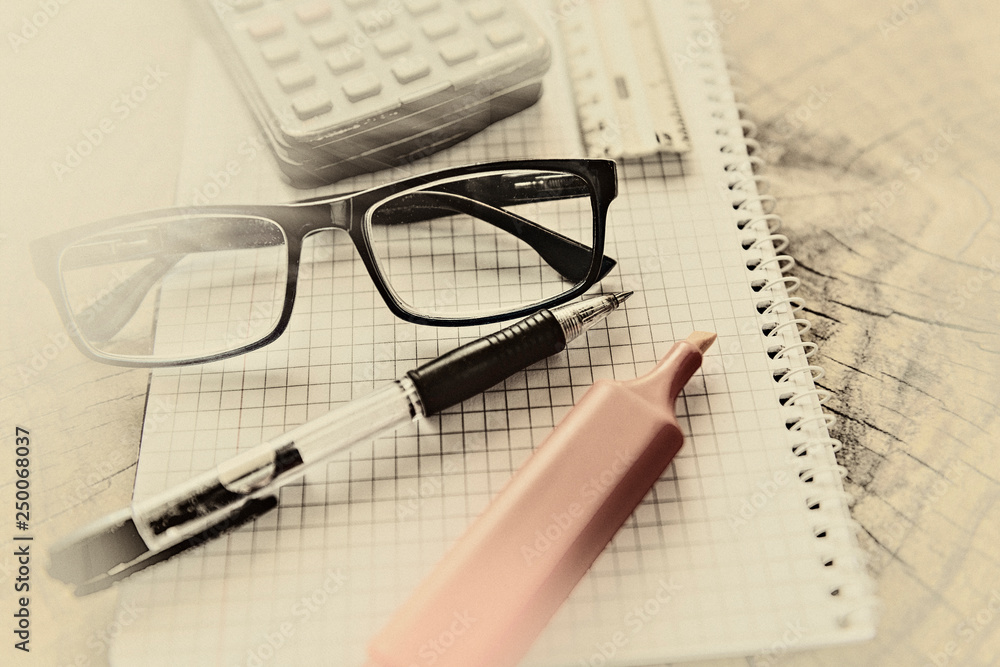 Fototapeta premium Marker pen, pen, eyeglasses, ruler and calculator on notebook. Close up, study, business and education concept. Image slightly blurred on foreground and background