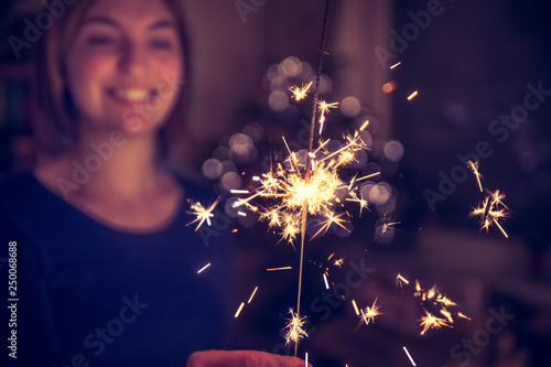 Happy girl is holding a sparkler at Christmas time