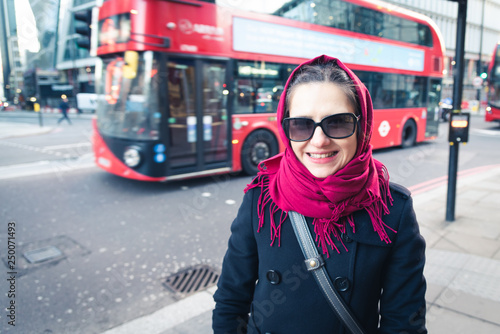 The beautiful tourist girl in London with a red bus in the background.