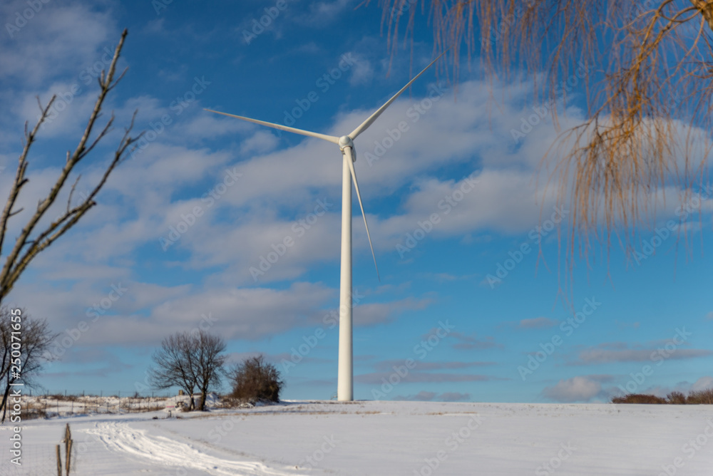 Fototapeta premium Grande éolienne dans un paysage en hiver avec de la neige sur fond de ciel bleu en Moselle
