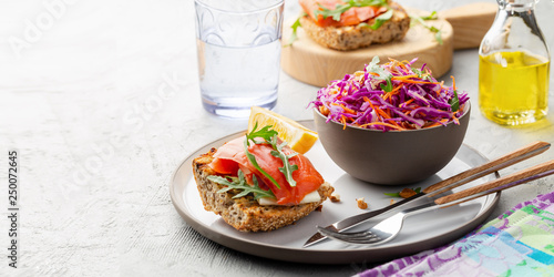 Coleslaw salad in a bowl and healthy sandwich with salmon. White background. Red cabbage and carrot 