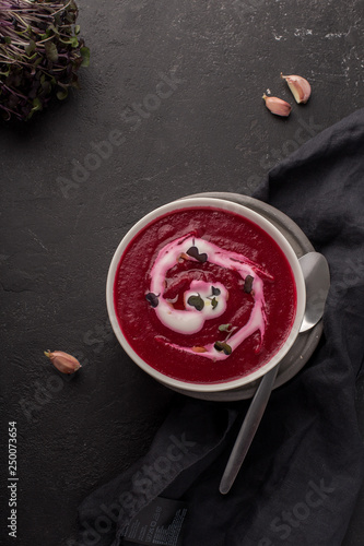 two plates with beetroot soup and sour cream on black background