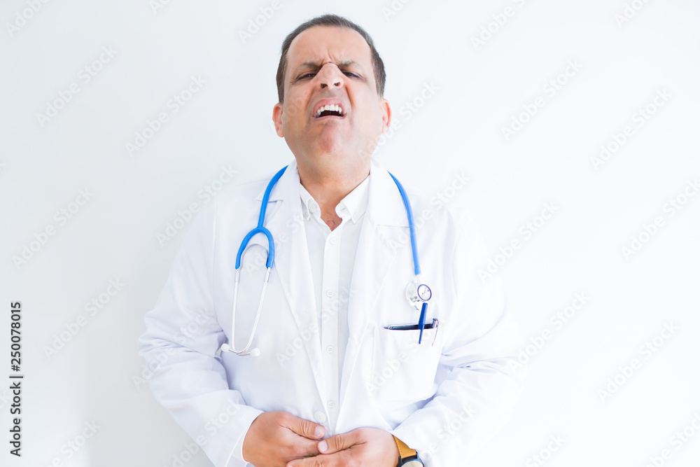 Middle age doctor man wearing stethoscope and medical coat over white background with hand on stomach because indigestion, painful illness feeling unwell. Ache concept. Middle age doctor man wearing stethoscope and medical coat over white background with hand on stomach because indigestion, painful illness feeling unwell. Ache concept.