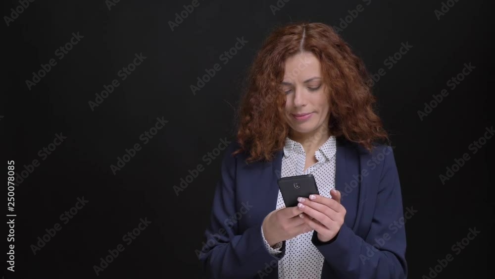 Closeup portrait of adult caucasian businesswoman browsing on the phone in front of the camera