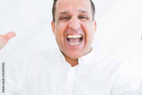 Middle age man celebrating and screaming happy for succesful win