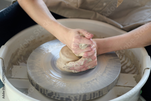 Woman making ceramic pottery on wheel, hands closeup, focus on potters, palms with pottery