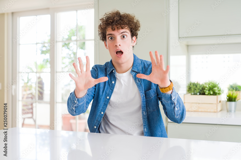 Young handsome man wearing casual denim jacket at home afraid and terrified with fear expression stop gesture with hands, shouting in shock. Panic concept. Young handsome man wearing casual denim jacket at home afraid and terrified with fear expression stop gesture with hands, shouting in shock. Panic concept.