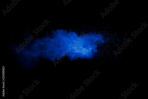 Abstract art blue powder on black background.