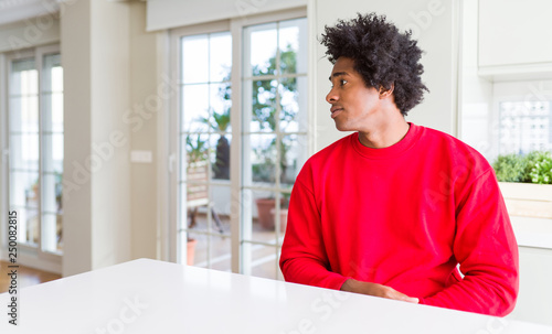 African American man wearing casual red sweatshirt looking to side, relax profile pose with natural face with confident smile.