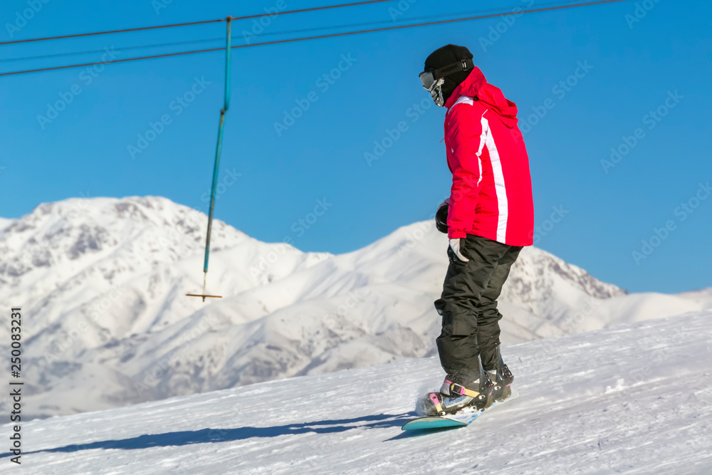 snowboarder quickly rolls down the mountain in loose snow against a blue sky on a sunny day. Copy space