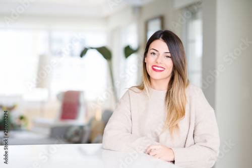 Young beautiful woman wearing winter sweater at home with a happy and cool smile on face. Lucky person.