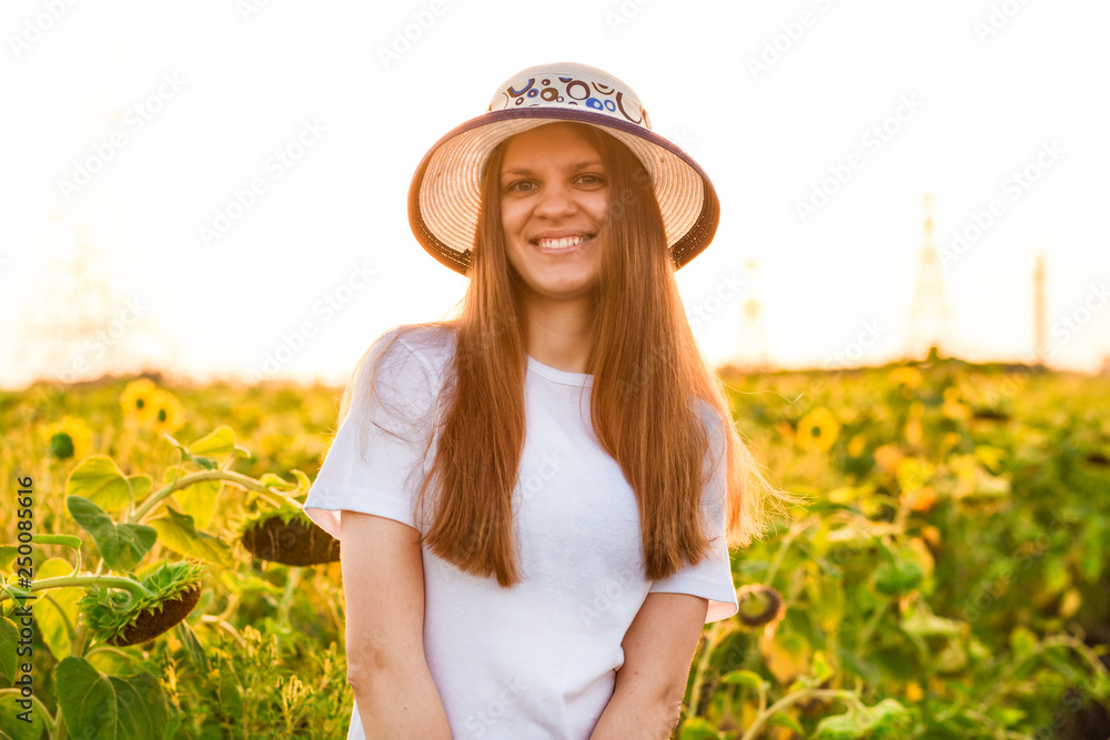 Summer portrait of happy young woman in white with flying hair in sunflower field