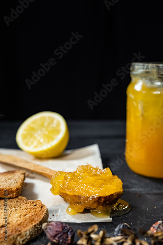 Spoonful of honey on dark rustic background. Crystallized home-made honey in jar, low-key shot with copy space photo