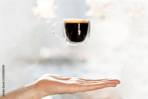 cup of coffee soars in the air above the hand