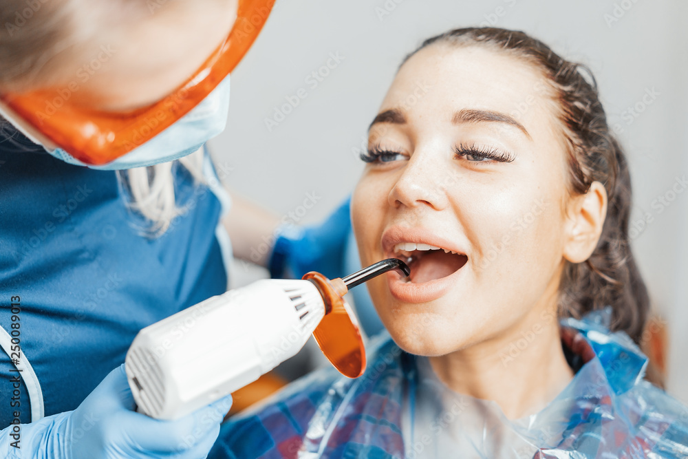 Close up of woman dentist in blue uniform holding curing lamp. Close up of woman dentist in blue uniform holding curing lamp.