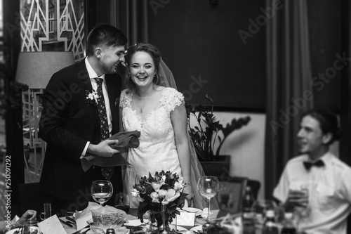 Newlywed couple laughing at wedding reception in restaurant, bride and groom having fun with friends and family, romantic moment, marriage concept