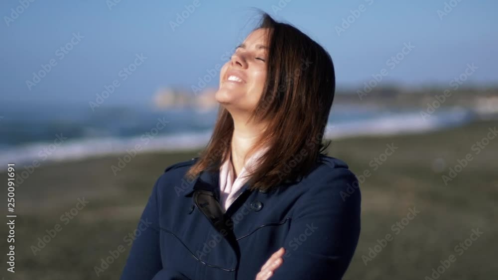 Happy beautiful woman feeling the light of sun on skin in front of the sea Happy beautiful woman feeling the light of sun on skin in front of the sea