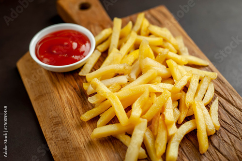 French fries with ketchup on a cutting board, background is concrete