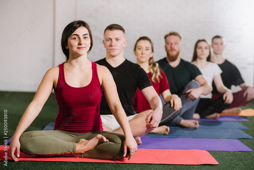 A group of young people sitting in yoga pose behind each other A group of young people sitting in yoga pose behind each other