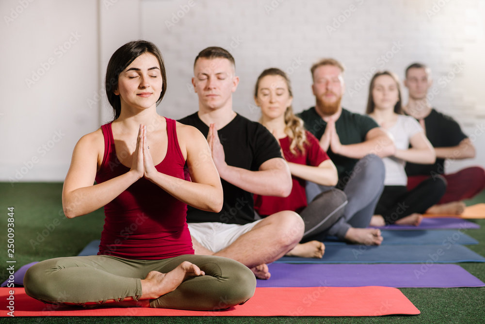 A group of young people sitting in yoga pose behind each other A group of young people sitting in yoga pose behind each other