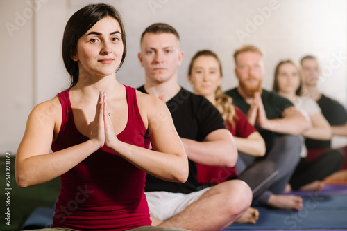 A group of young people sitting in yoga pose behind each other