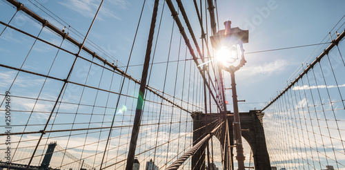 The sun shines from the piers of the Brooklyn Bridge