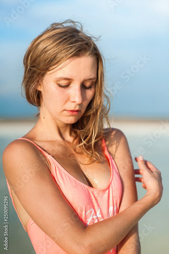 Summer lifestyle fashion portrait of young stunning blonde woman. Sunbathing, enjoying life. Wearing stylish pink swimsuit. Young beautiful woman in pink swimsuit with fashion hairdo. Close up