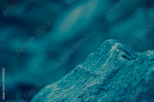 Granite rocks in blue-green tinting. Granite close up. Texture of the stone with blue color. Background from natural material with cool shades