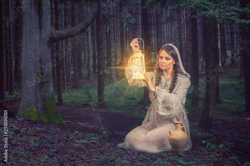 Fotografia Woman wearing robe illuminates a place in the forest with a lantern