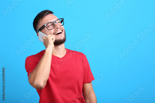 Young man talking on a mobile phone on blue background