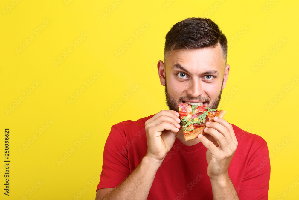 Young man eating pizza on yellow background Young man eating pizza on yellow background