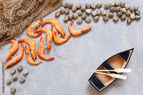 Fresh raw Surf clam chamelea gallina, shrimps, fishing boat with oars and  fishnet. Top view, close up on light concrete background photo