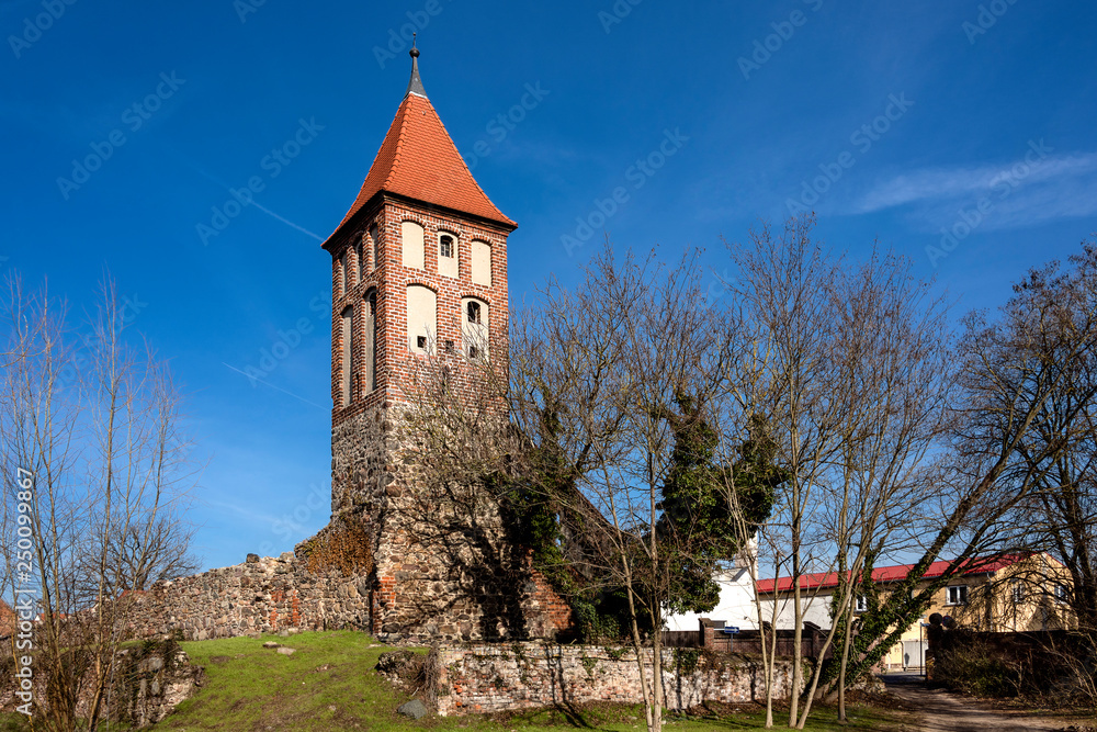 Germany, Brandenburg, Jueterbog: Panorama view of historic tower as part of the old city wall in the city center of the German town with park and blue sky in the background - concept travel history