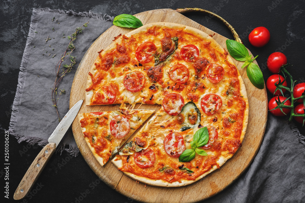 Margarita homemade pizza on a cutting board, dark stone background. Top view, flat lay. Margarita homemade pizza on a cutting board, dark stone background. Top view, flat lay.