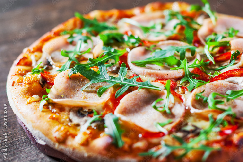 Pizza with Mozzarella cheese, mushrooms, ham, tomato sauce, pepper, Spices and Fresh arugula. Italian pizza on wooden table background Pizza with Mozzarella cheese, mushrooms, ham, tomato sauce, pepper, Spices and Fresh arugula. Italian pizza on wooden table background