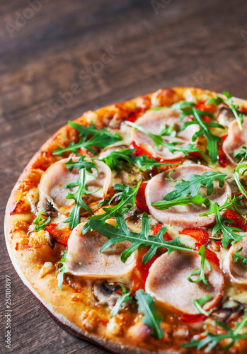 Pizza with Mozzarella cheese, mushrooms, ham, tomato sauce, pepper, Spices and Fresh arugula. Italian pizza on wooden table background 