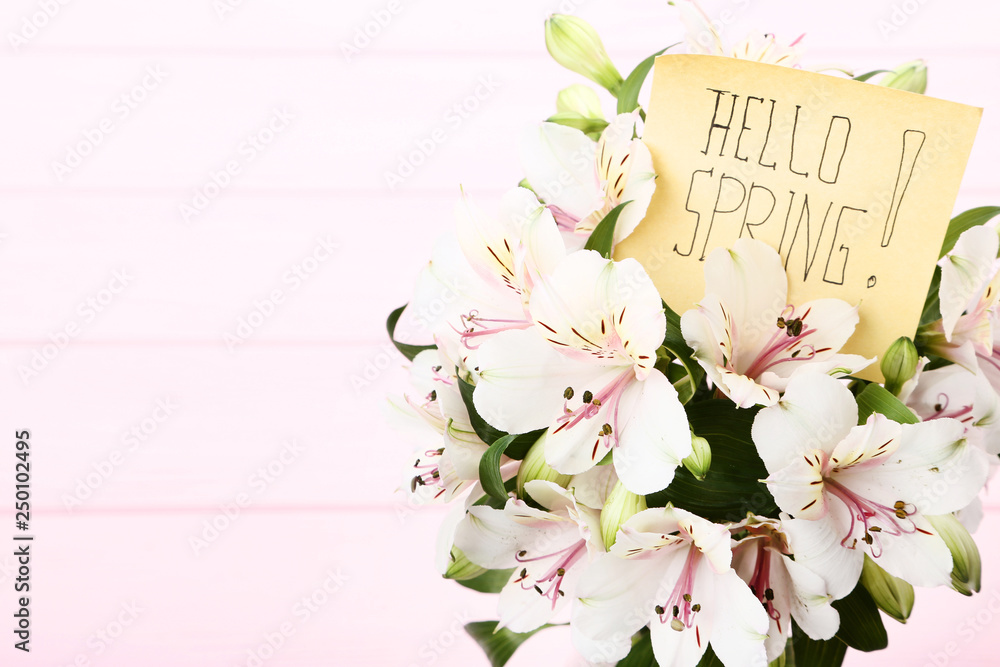 Bouquet of alstroemeria flowers with text Hello Spring on wooden background