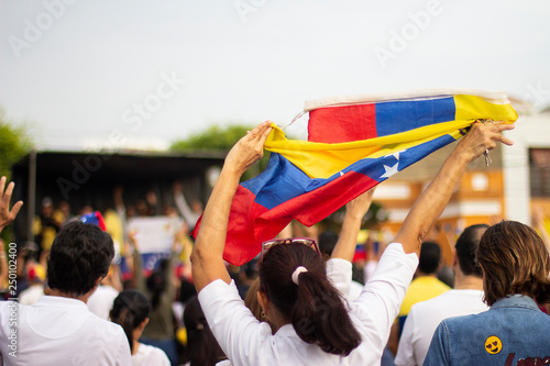 Woman vigorously holding Venezuelan flag at protest against Nicolas Maduro photo