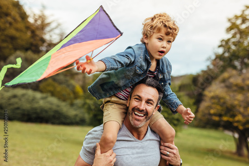 Foto Happy father and son flying kite outdoors