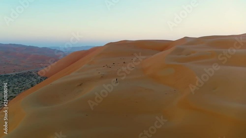 Aerial view of a man walking alone in the top of dunes, U.A.E. photo