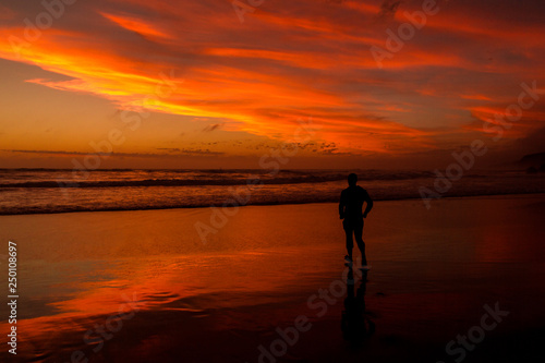 Young man walking outdoors watching the sunset at a beach. Thinking and relaxing concept. © Martin