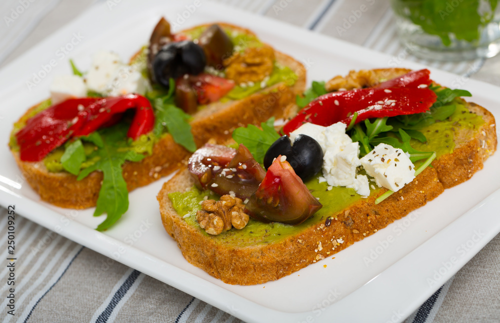 Toasts with guacamole, fresh vegetables, feta cheese