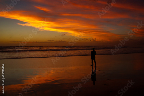 Young man walking outdoors watching the sunset at a beach. Thinking and relaxing concept. © Martin