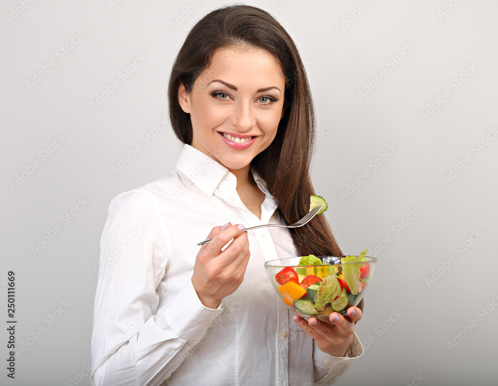 Beautiful smiling business woman eating healthy organic vegatable salad on the lunch on blue background with empty copy space. Healthy food at work time. Closeup