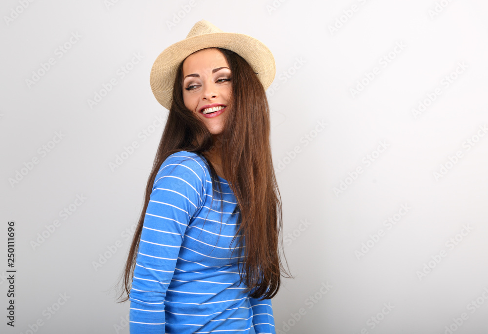 Friendly toothy smiling woman in blue top and straw hat posing and looking happy on blue color copy space Friendly toothy smiling woman in blue top and straw hat posing and looking happy on blue color copy space