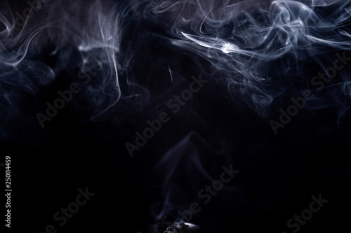 Vape smoke clouds isolated on black background. Hot vape liquid splash in vape coil. Nice aromatic cloud. Low light photo. Underexposed photo in a low key style.