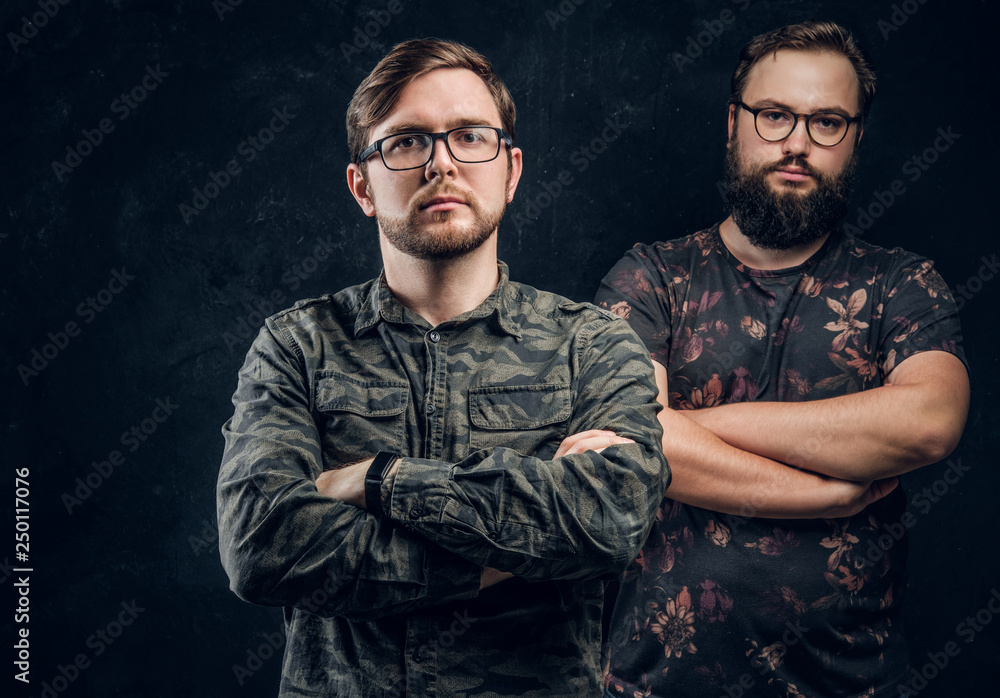 Two guys in trendy clothes posing with confident look and crossed arms. Studio photo with dark background Two guys in trendy clothes posing with confident look and crossed arms. Studio photo with dark background
