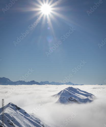 Canvas Print Mountain peaks covered in snow above clouds in La Plagne, French Alps