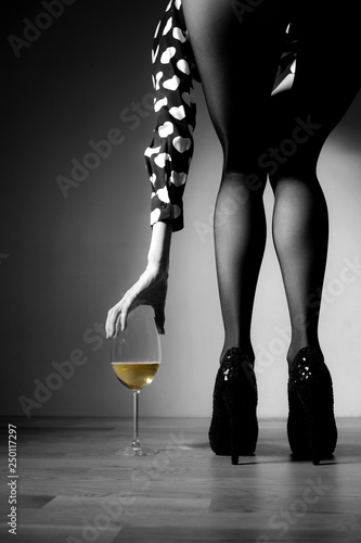 Canvas Print Beautiful girl legs and a glass of alcoholic beverage, black white photo, golde