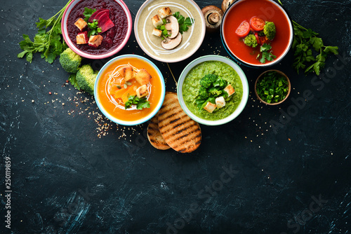 Assortment of colored vegetable cream soups. Dietary food. On a black stone background. Top view. Free copy space.